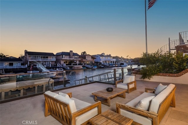 patio terrace at dusk featuring an outdoor living space and a water view