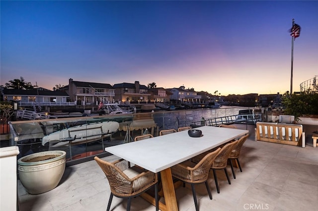 patio terrace at dusk featuring a water view