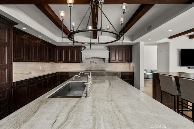 kitchen featuring pendant lighting, custom exhaust hood, sink, light stone countertops, and tasteful backsplash