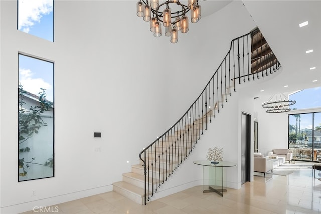 stairs with tile patterned floors, a chandelier, a healthy amount of sunlight, and a high ceiling