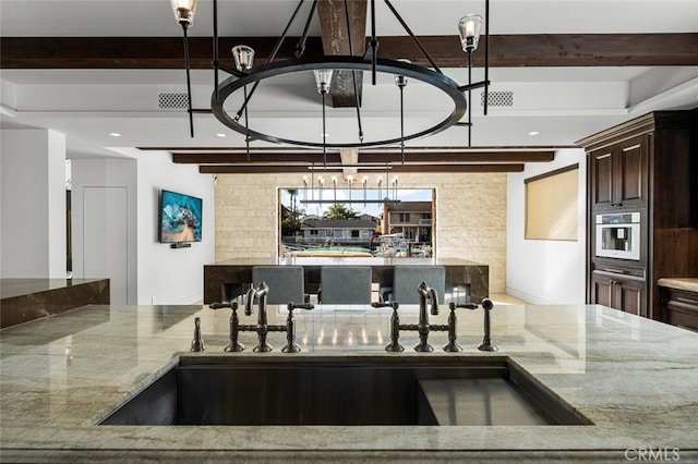 kitchen with beam ceiling, sink, oven, and stone countertops