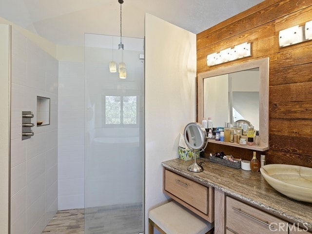 bathroom with vanity, a tile shower, and wood walls