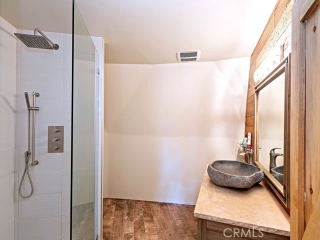 bathroom featuring vanity, a tile shower, and hardwood / wood-style floors