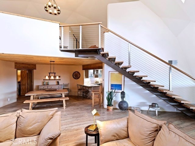 living room with a towering ceiling, a notable chandelier, and hardwood / wood-style flooring