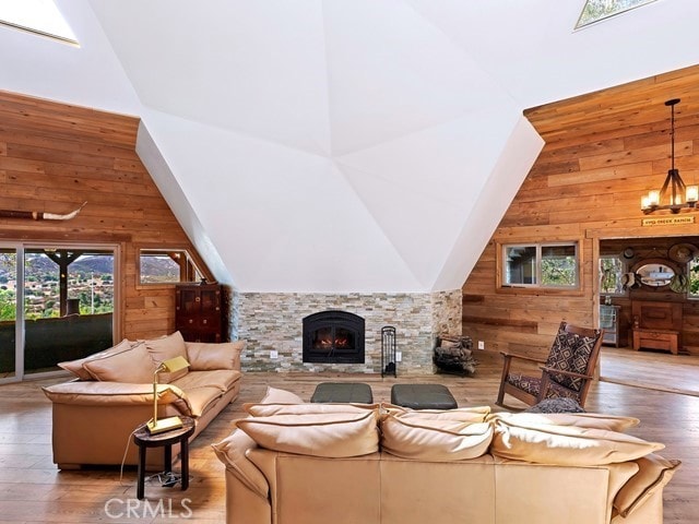 living room featuring hardwood / wood-style floors, wooden walls, high vaulted ceiling, and a fireplace