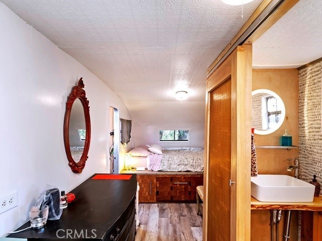 bedroom featuring a textured ceiling, sink, and light wood-type flooring