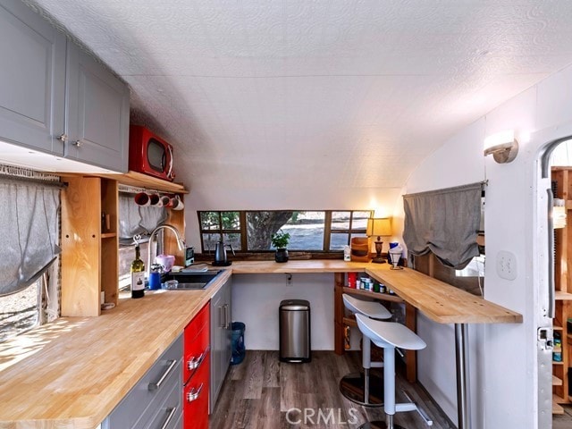 kitchen featuring lofted ceiling, dark hardwood / wood-style flooring, and wooden counters