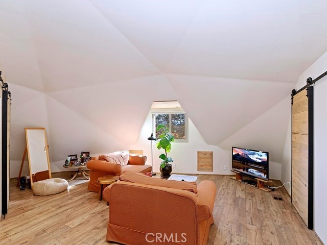 interior space featuring light hardwood / wood-style flooring, a barn door, and vaulted ceiling