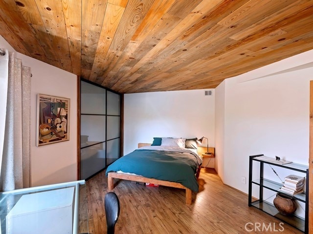 bedroom with wood ceiling, hardwood / wood-style flooring, and vaulted ceiling