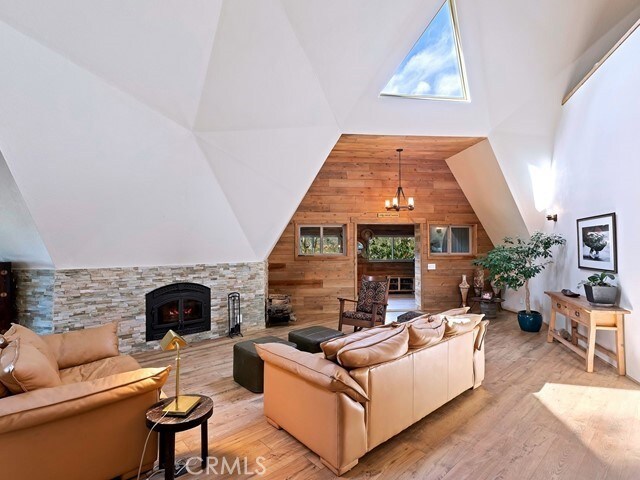 living room featuring an inviting chandelier, light hardwood / wood-style flooring, wood walls, and a healthy amount of sunlight