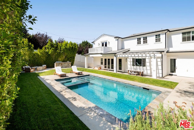 back of property featuring a yard, a balcony, a patio area, and a pool with hot tub