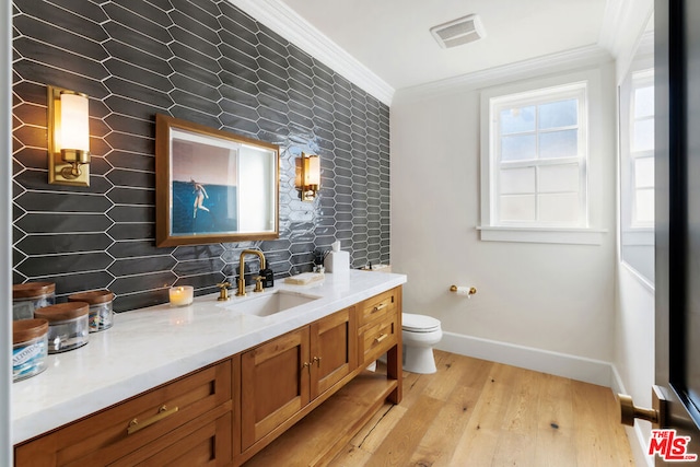 bathroom featuring hardwood / wood-style floors, decorative backsplash, ornamental molding, and vanity