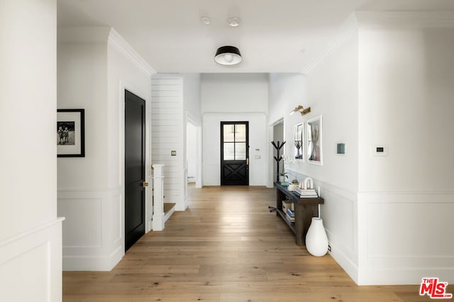 corridor with light hardwood / wood-style floors and crown molding