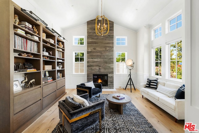 living room featuring high vaulted ceiling, an inviting chandelier, wooden walls, a fireplace, and light hardwood / wood-style floors