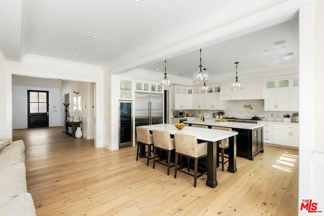 kitchen featuring white cabinets, light hardwood / wood-style floors, a kitchen island with sink, and built in fridge