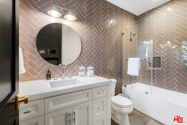 full bathroom with combined bath / shower with glass door, tile patterned floors, vanity, tile walls, and toilet