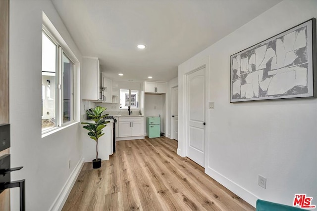 corridor featuring plenty of natural light, light hardwood / wood-style floors, and sink