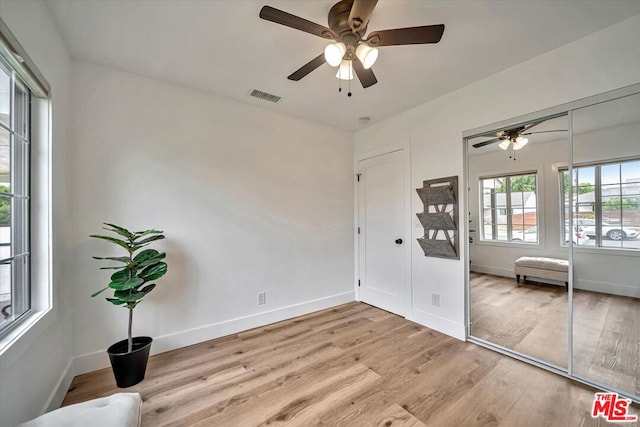 unfurnished bedroom with ceiling fan, a closet, and light wood-type flooring