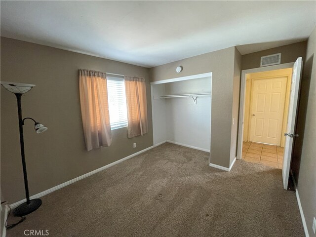 unfurnished bedroom featuring light carpet and a closet