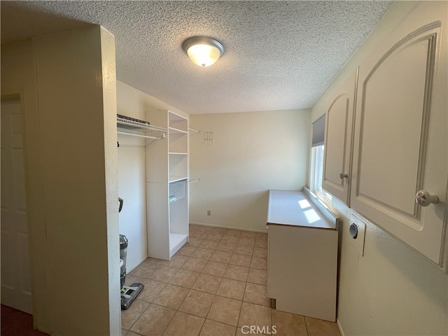 laundry room featuring a textured ceiling and light tile patterned floors