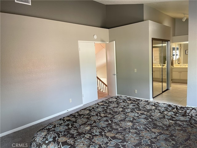 unfurnished bedroom featuring connected bathroom, a closet, and light tile patterned floors