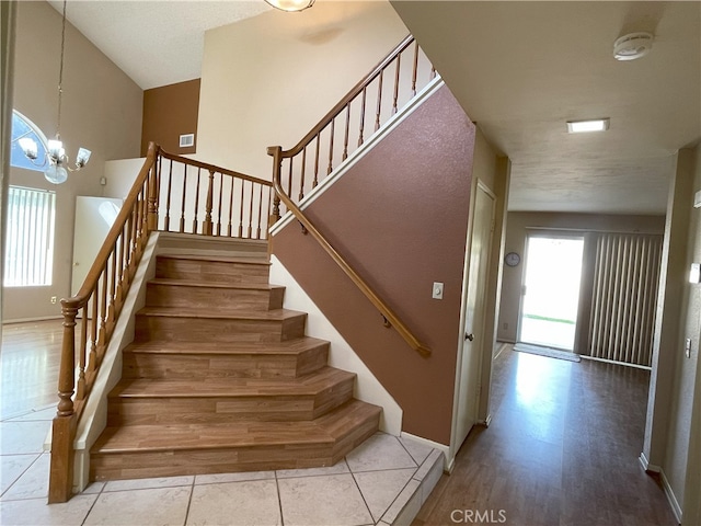 stairway with hardwood / wood-style floors, a textured ceiling, and an inviting chandelier