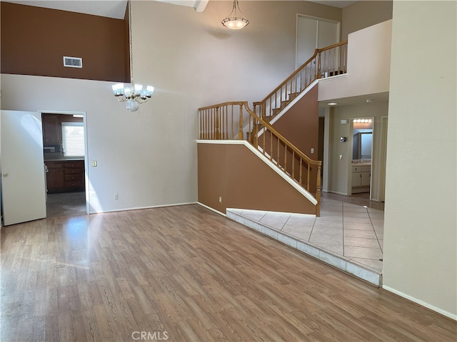 unfurnished living room featuring a high ceiling, light hardwood / wood-style flooring, and a chandelier