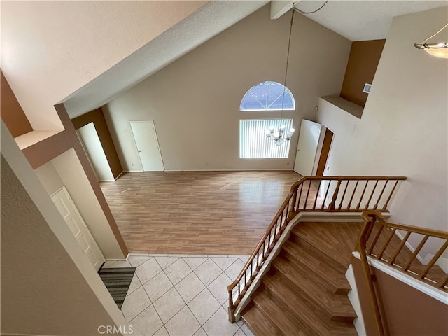 staircase featuring a notable chandelier, beam ceiling, high vaulted ceiling, and wood-type flooring