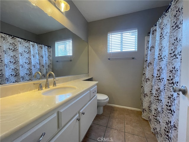 bathroom with a wealth of natural light, vanity, toilet, and tile patterned floors