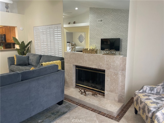 living room featuring a tiled fireplace, lofted ceiling, and light tile patterned floors