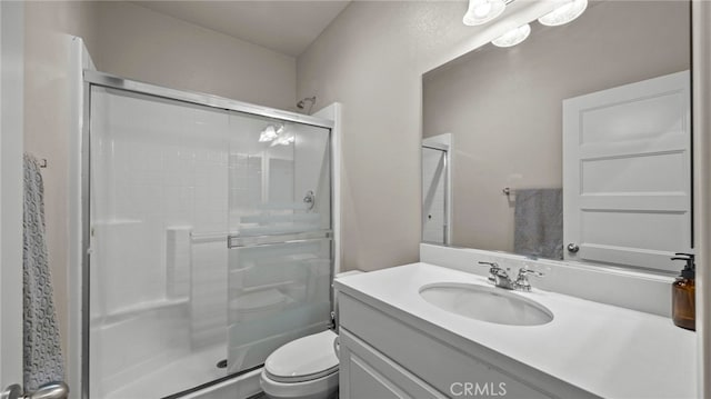 bathroom featuring toilet, vanity, and a shower with door