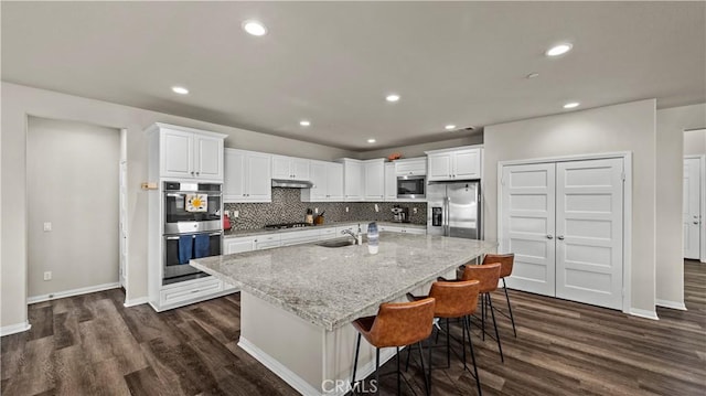 kitchen with a center island with sink, sink, a breakfast bar area, stainless steel appliances, and white cabinets