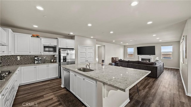 kitchen featuring sink, white cabinetry, appliances with stainless steel finishes, an island with sink, and a breakfast bar area