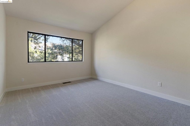 carpeted empty room featuring lofted ceiling