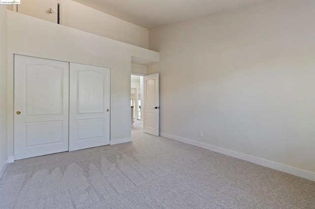 unfurnished bedroom featuring light carpet and a closet