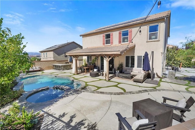 back of house featuring area for grilling, a pool with hot tub, an outdoor living space, a patio area, and an outdoor bar