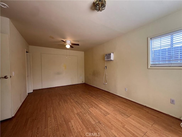 unfurnished room featuring light wood-type flooring, a wall unit AC, and ceiling fan