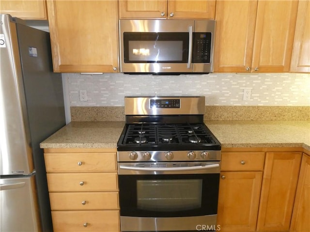 kitchen featuring light stone countertops, backsplash, and stainless steel appliances