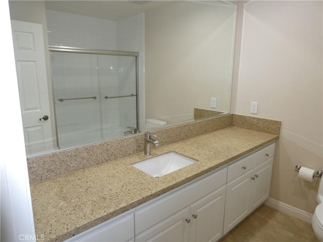 bathroom featuring vanity, toilet, and a shower with door