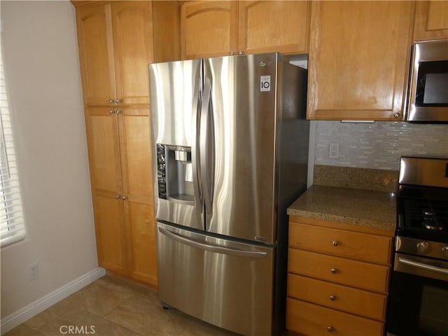 kitchen with backsplash, light stone countertops, light tile patterned floors, and appliances with stainless steel finishes