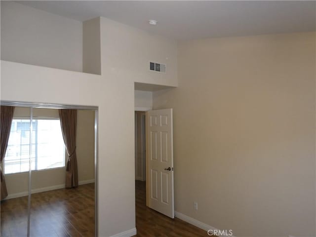 empty room with a towering ceiling and dark hardwood / wood-style floors