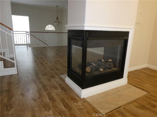 room details with a multi sided fireplace, wood-type flooring, and crown molding