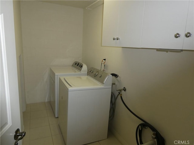 laundry room featuring cabinets, washing machine and dryer, and light tile patterned flooring