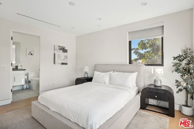 bedroom featuring ensuite bathroom and light wood-type flooring