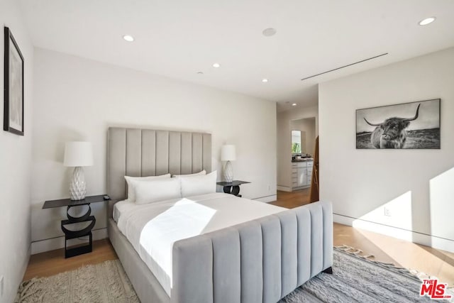 bedroom featuring ensuite bath and light wood-type flooring