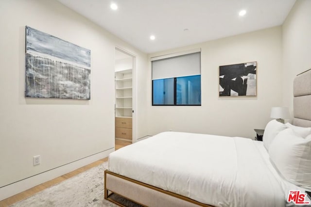 bedroom featuring hardwood / wood-style floors, ensuite bathroom, a spacious closet, and a closet