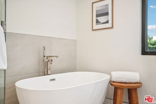 bathroom featuring a bathtub and tile walls