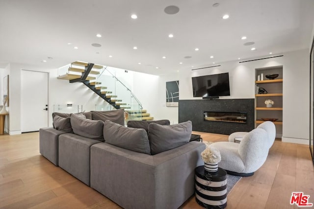 living room featuring light hardwood / wood-style floors, built in features, and a fireplace