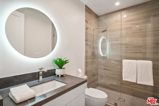 bathroom featuring vanity, a shower with shower door, and toilet