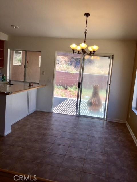 unfurnished dining area with an inviting chandelier and dark tile patterned floors